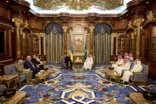 Reuters Ukraine's President Volodymyr Zelenskiy is black and the Crown Prince of Saudi Arabia, Mohammed bin Salman Al Saud is next to him. Advisors sit on either side in a grand meeting room with blue carpet