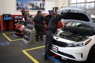 Workers inspect vehicles at an oil change location in Indianapolis.