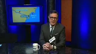 A middle-aged man at a public access TV set with a map behind him on a screen.