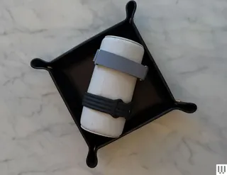 Two smartwatch wristbands on a cylindrical cushion in a black tray