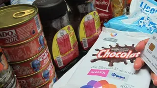 超市收銀處，一名消費者手持信用卡，周圍擺放著各類雜貨