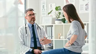 A mature doctor sitting and talking with a patient in a clinic during a consultation