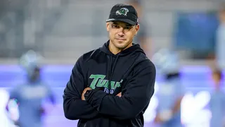 Tulane head coach Jon Sumrall watching players on the sideline during a football game