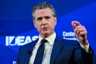 Man in suit and tie gesturing and speaking on stage.