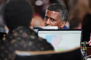 a man looking at another person behind a computer