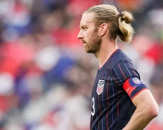 Tim Ream in a dark pinstriped USA jersey with captain's armband stands in profile