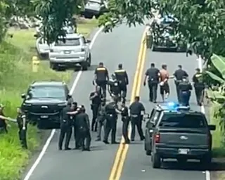 Police arrest a shirtless man on a roadway full of law enforcement vehicles