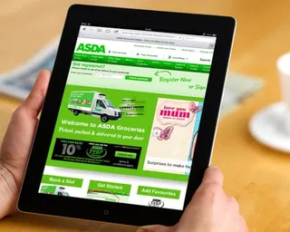 Someone sitting at a table looks at the Asda website on a tablet