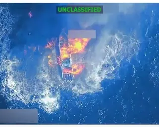 Aerial, color view of fireball above boat on ocean.