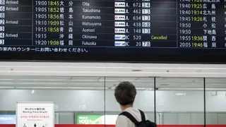 台风“蔷薇”逼近日本本土，影响飞机起降，一名男子周一在东京羽田机场查看航班资讯，上面显示飞往冲绳的航班已被取消。（图取自法新社）