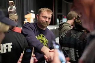Smiling man in long-sleeved T-shirt shakes hands with people.