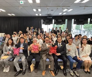 文化部駐日本代表處台灣文化中心主辦的「剪花・綻放－台灣剪紙藝術在馬祖」特展2日開幕，駐日副代表周學佑（右3）、台灣文化中心主任曾鈐龍（右4）舉著參展藝術家陳治旭（右2）於開幕式上現場完成的剪紙作品，與全場來賓合影。中央社記者戴雅真東京攝　115年6月2日