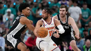 New York Knicks guard Jalen Brunson spinning with basketball as San Antonio Spurs guard Dylan Harper defends