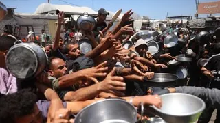 流离失所的巴勒斯坦民众周四在加沙地带南部汗尤尼斯，争先恐后领取由慈善厨房分发的热餐。（图取自法新社）