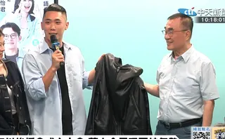 民眾黨新北市議員陳世軒6日代表白營小雞致贈李四川一件黃仁勳的標誌黑皮衣。（圖／中天新聞）