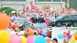 2019年6月21日，朝鮮平壤國際機場外，朝鮮領導人金正恩與中國國家主席習近平站在車隊中，向人群揮手。