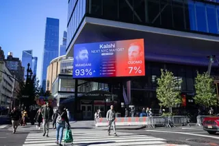 A large digital billboard displays NYC mayoral election odds showing Mamdani at 93% and Cuomo at 7% above a busy street