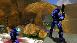 Halo Combat Evolved Anniversary: A screenshot of multiplayer gameplay, showing two blue spartans in the foreground firing at a group of red spartans in the distance.