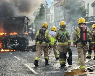 Firefighters extinguish a bus that was set alight in Belfast
