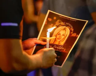 a person holds a candle and a sheet of paper with a photo of a young woman