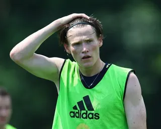 Scott McTominay in a bright green training bib runs his hand through his hair during training