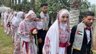 Couples in their wedding clothes walking in a line.