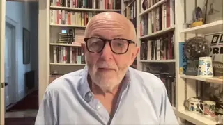 BBC International editor Jeremy Bowen wearing pale blue shirt and sitting in front of bookshelf