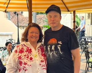 Gina Rinehart and Elon Musk stand together under a striped canopy
