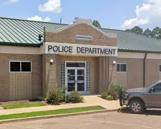exterior of tan police department building with car parked outside