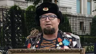 Facebook/Semyon Skrepetsky A man wearing an old-style Russian hat with a Soviet badge holds the top of a framed picture and wears a jacket crammed with medals