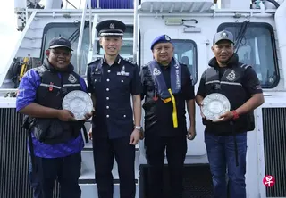 警察海岸卫队司令洪湧胜高级助理警察总监（左二）为阿兹列（左一）和凯里（右一）颁发SaferSG公民意识奖。 （新加坡警方提供）