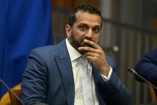 a man in a suit sits with his hand over his mouth
