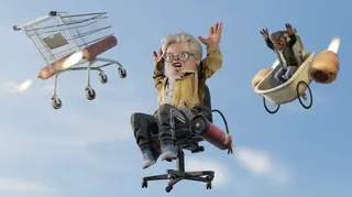 A scared man sits on an office chair mid-air while a trolley and a bath with wheels falls behind him