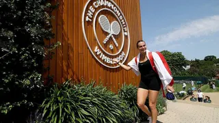 Women's world number one Aryna Sabalenka poses in front of a giant Wimbledon crest as she prepares to practice at the All England Club