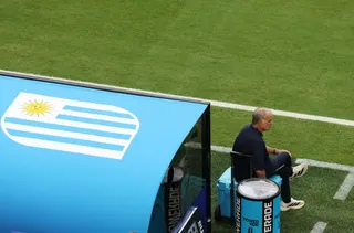 Marcelo Bielsa sits on the drinks cooler by the Uruguay dugout.