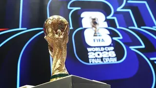 The World Cup trophy in front of the logo for the 2026 World Cup