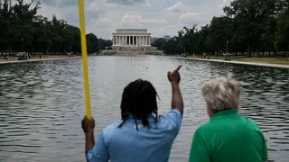 A worker provides a visitor with directions as he cleans the waters of the Lincoln Memorial Reflecting Pool following the completion of recent renovations in Washington, DC, on June 22, 2026.