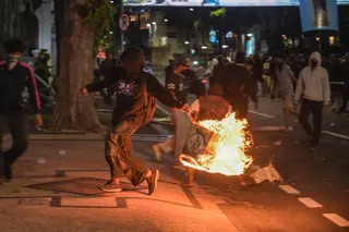 A student throws a box that has been set on fire at riot police during a protest in Surabaya on Friday. Photo: AFP