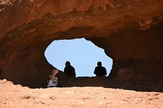 people sitting by rock opening