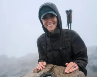 The Princess of Wales posing by a trig point in waterproof climbing clothes in fog