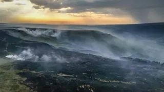 Shot of rolling moorland hills which are blackened and smoking
