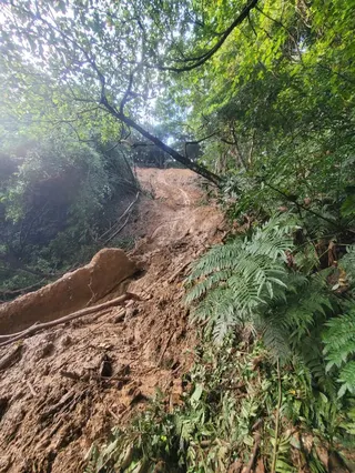 台北已停業的「圓山保齡球館」遭巨石滑落砸穿，後山因溝狀侵蝕，步道下方已懸空，現場畫面曝光。（圖／翻攝畫面）