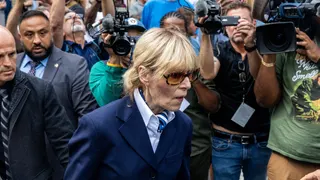 Writer E. Jean Carroll walks past a group of photographers outside a courthouse.