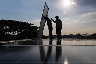 Workers install solar panels onto the roof of a home in Manila on April 30. Photo: AP