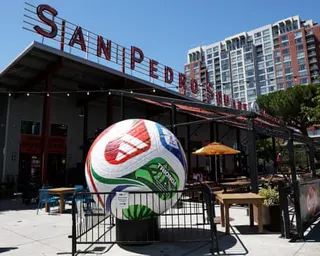 a large soccer ball statue fenced off in a public area