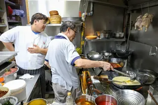 A Qantas lounge chef learning how to cook a dish from Wing Seong Fatty’s restaurant.