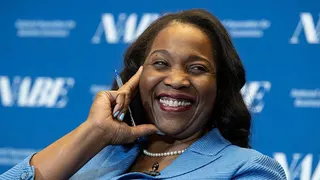 Lisa D. Cook, a member of the Board of Governors of the Federal Reserve, smiles while holding her hand against her face. She is wearing a blue suit and speaks at The Capital Hilton during the 42nd annual National Association for Business Economics Economic Policy Conference on February 24, 2026 in Washington, DC.
