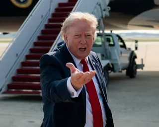a man holds his hand out while speaking near an airplane