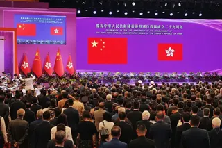 2026年7月1日，在香港灣仔的香港會議展覽中心，現場舉辦慶祝香港成立29週年活動。多人站著背向鏡頭，眼望前方的中國國旗及特區區旗。