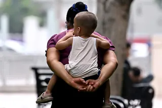 This photo taken on June 29, 2026, shows a woman carrying a child on her back while walking in a flower garden in Hanoi. One year after lifting its longstanding two-child limit, Vietnam is actively encouraging people to have more babies as the communist country risks getting old before it gets rich. — AFP pic